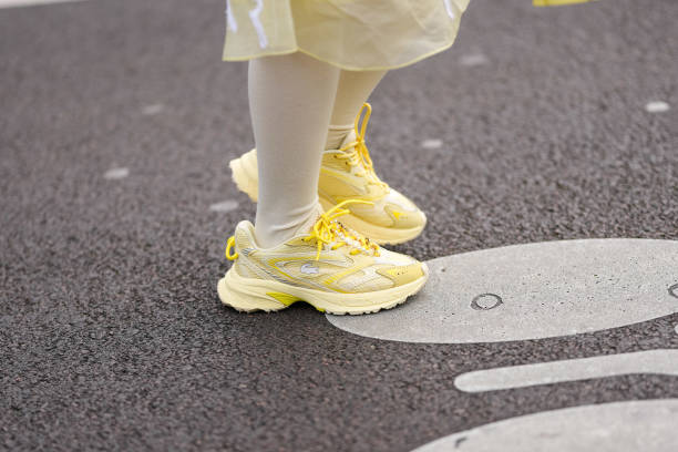 Valerie Zhang wears white knee high socks, bright yellow sneaker shoes, outside Lacoste, during the Paris Fashion week Women's Fall/Winter 2025-2026...