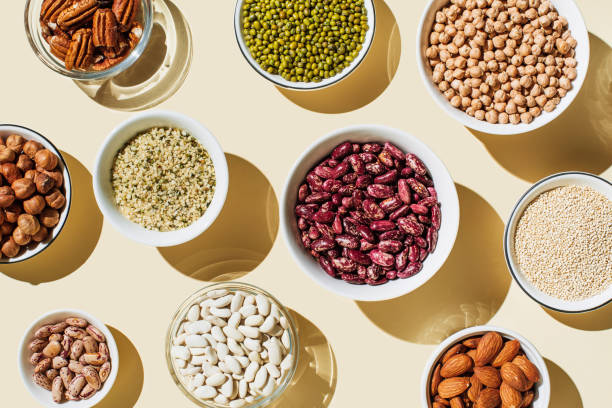various kinds of vegan protein sources on beige background. set of food supplements. gluten free cereals as ground hemp seeds, quinoa. nuts and legumes (green mung beans, chick-pea, red lentil, kidney bean, almonds, hazelnuts
