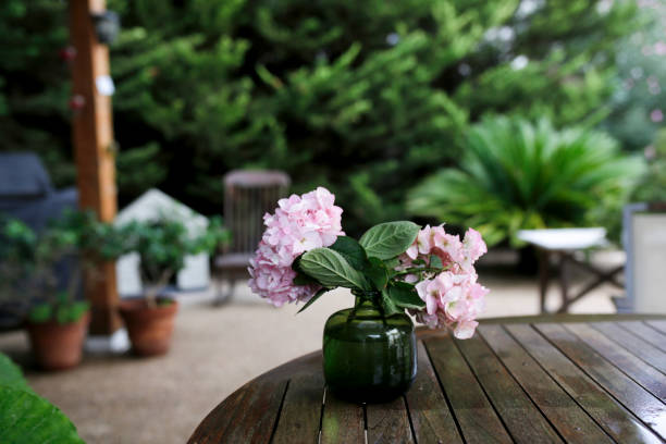 vase with pink hydrangeas on a wood garden table - garden decoration stock-fotos und bilder