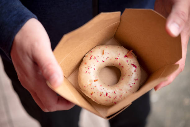vegan gourmet donut with rose petals in cardboard container - junk food stock pictures, royalty-free photos & images