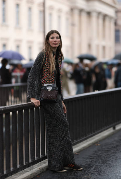 Veronika Heilbrunner is seen outside Chanel show wearing pearl earrings, grey tweed jacket and matching Chanel pants, burgundy and black crossbody...