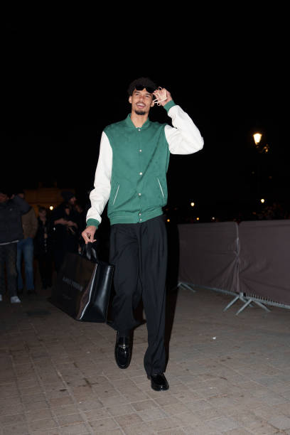 Victor Wembanyama wears sunglasses, a green and white teddy jacket with monogram logo print from Louis Vuitton, black flared pants, black leather...
