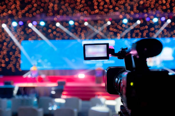 video camera operator working with his equipment at indoor event. cameraman silhouette at meeting room - concert stock pictures, royalty-free photos & images
