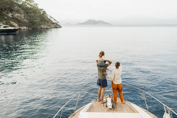 view from behind of happy family travelling with baby on board of luxury yacht. unrecognizable people - travel stock pictures, royalty-free photos & images