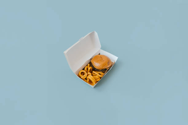 view of a hamburger and fries with open box on light blue plain background. - junk food stock pictures, royalty-free photos & images