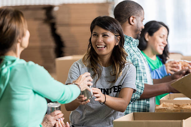 volunteer accepts canned food donation at food drive - food stock pictures, royalty-free photos & images
