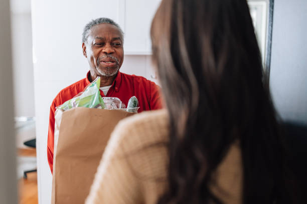 volunteer delivering food for senior man - food stock pictures, royalty-free photos & images