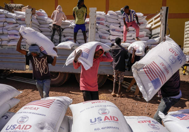 Volunteers at the Zanzalima Camp for Internally Displaced People unload 50 kilogram saks of Wheat flour that were a part of an aid delivery from...