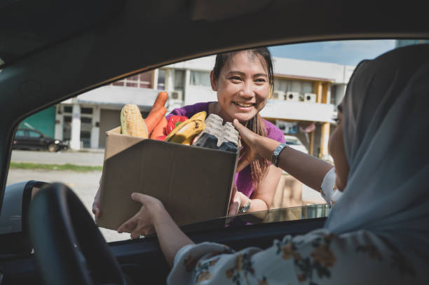 volunteers hands out food at drive through food bank - food stock pictures, royalty-free photos & images