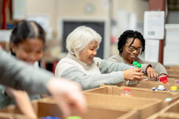 volunteers packing at a local food bank - food stock pictures, royalty-free photos & images