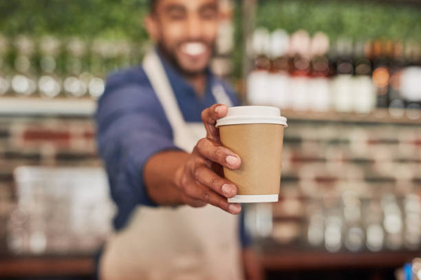 waiter, coffee cup and man giving drinks in cafe, shop or restaurant. closeup barista, takeaway beverage and tea latte for hospitality service, fast food worker or catering startup in cafeteria lunch - coffee stockfoto's en -