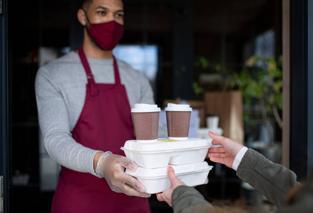 waiter giving take away food to customer in restaurant, coronavirus and new normal concept. - junk food stock pictures, royalty-free photos & images