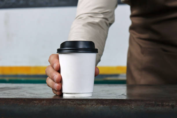 waiter holding and serving a paper cup of hot coffee - junk food stock pictures, royalty-free photos & images