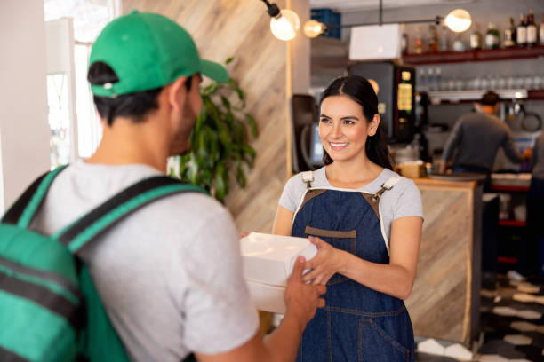 waitress handling a food order to a delivery person at a dark kitchen - junk food stock pictures, royalty-free photos & images