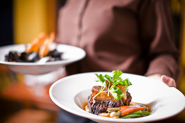waitress holding plate of beef tenderloin - food stock pictures, royalty-free photos & images