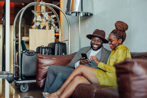 wealthy couple with smartphone in hotel lounge. - travel stock pictures, royalty-free photos & images