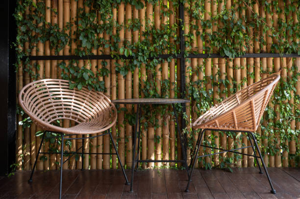 wicker chair against a bamboo wall covered with ivy. - garden decoration stockfoto's en -beelden