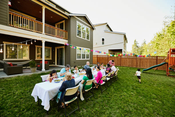 wide shot family sharing a meal in backyard during birthday party - garden decoration stockfoto's en -beelden