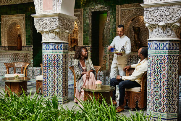 wide shot of couple being served tea in courtyard of luxury hotel - travel stock pictures, royalty-free photos & images