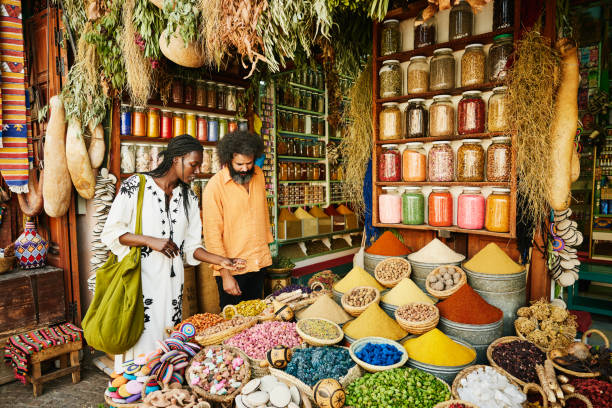 wide shot of couple shopping in spice shop in the souks of marrakech - food stock pictures, royalty-free photos & images