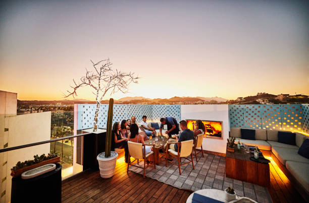 wide shot of families enjoying dinner on rooftop at resort during sunset - travel stock pictures, royalty-free photos & images