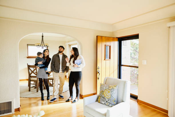 wide shot of family looking at home for sale with real estate agent - home decoration photos et images de collection
