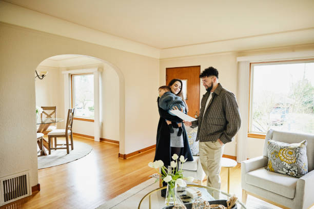 wide shot of family looking at sales sheet in home for sale - home decoration stockfoto's en -beelden