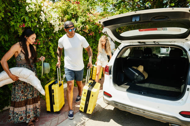 wide shot of family preparing to load rental car with luggage - travel stock pictures, royalty-free photos & images