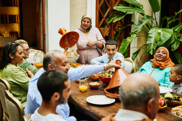 wide shot of multigenerational family serving food during celebration - food stock pictures, royalty-free photos & images