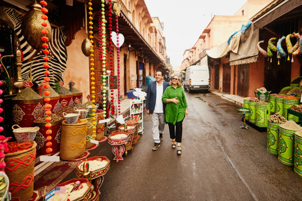 wide shot of senior couple admiring spice shops in the medina of marrakech - travel stock pictures, royalty-free photos & images