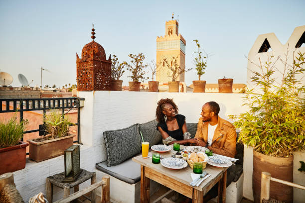 wide shot of smiling couple dining at rooftop restaurant in marrakech - travel stock pictures, royalty-free photos & images