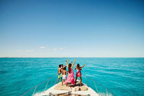 wide shot of smiling family dancing on bow of yacht during vacation - travel stock pictures, royalty-free photos & images