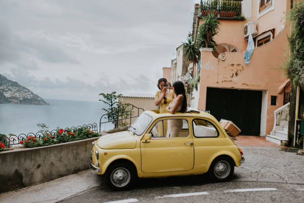 wide shot of two woman in a small, open topped, vintage yellow car. - travel stock pictures, royalty-free photos & images