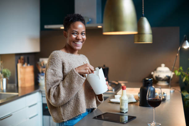 woman at home relaxing and eating take away food. - junk food stock pictures, royalty-free photos & images