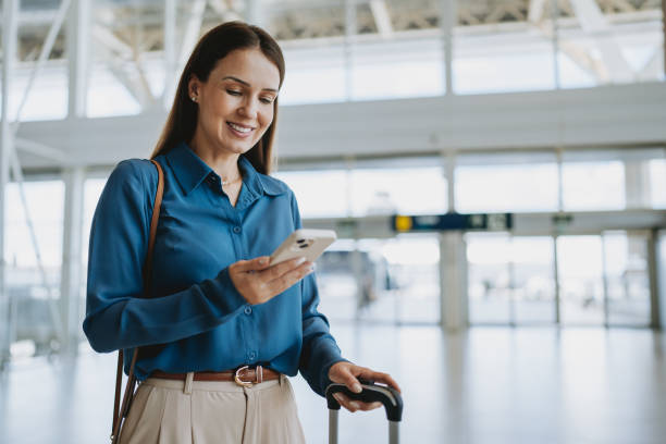 woman at the airport holding smartphone - travel stock pictures, royalty-free photos & images