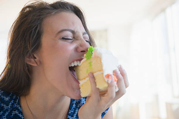 woman biting piece of cake - junk food stock pictures, royalty-free photos & images
