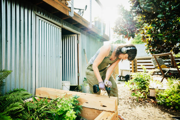 woman building raised garden beds in backyard on summer afternoon - home decoration stock pictures, royalty-free photos & images