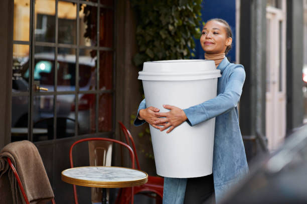 woman carrying large disposable coffee cup outside cafe - junk food stock pictures, royalty-free photos & images