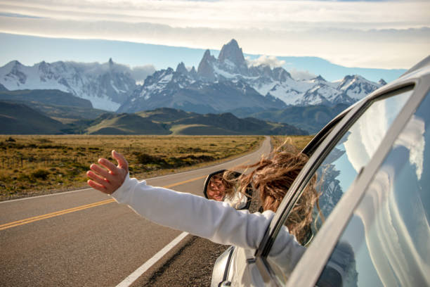 woman chilling and holding her hand outside of window while on the highway to the dramatic mountain range with fitz roy mountain in the middle - a road to el chalten from el calafate, argentina - travel photos et images de c