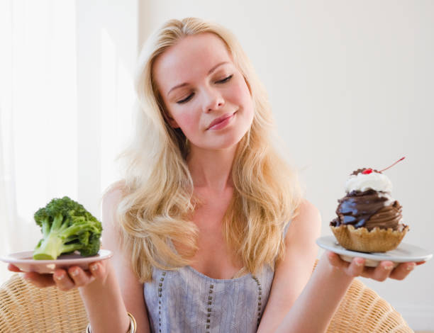 woman choosing between broccoli or sundae - junk food stockfoto's en -beelden