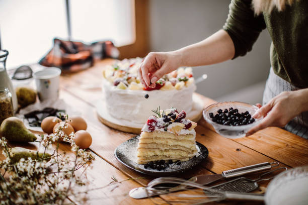 woman cut a piece of cake for the birthday celebrant - home decoration stock pictures, royalty-free photos & images
