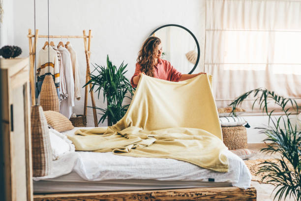 woman doing her morning routine, arranging pillows and making up bed at home. - home decoration stock pictures, royalty-free photos & images