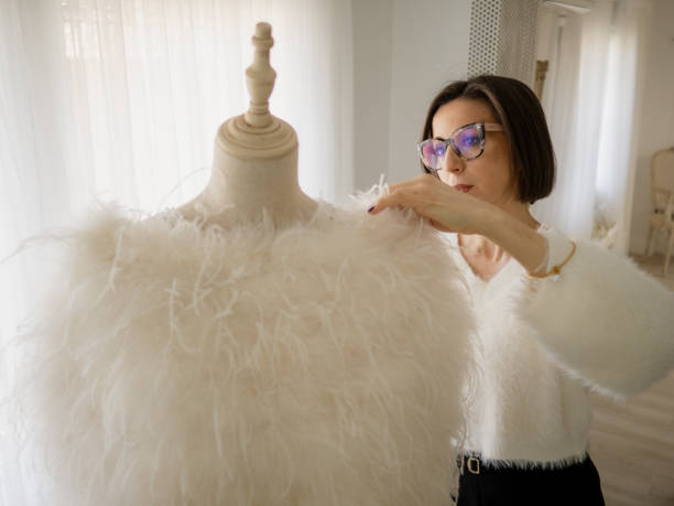 woman dressmaker putting a dress on a mannequin - fashion week stock-fotos und bilder