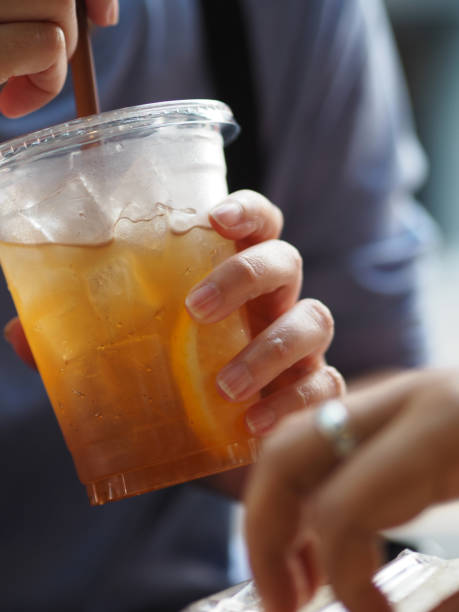woman drink fresh lemon tea close up view of ice cubes in cold brewed iced tea in clear glass, drink beverage - junk food stock pictures, royalty-free photos & images