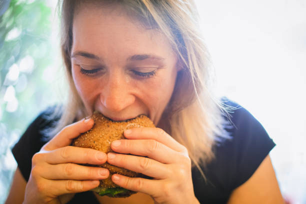 woman eating a burger - junk food stock pictures, royalty-free photos & images