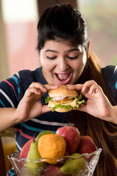 woman eating a fast food burger - junk food stock pictures, royalty-free photos & images