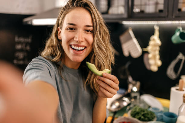 woman eating avocado and taking selfie - food stock pictures, royalty-free photos & images
