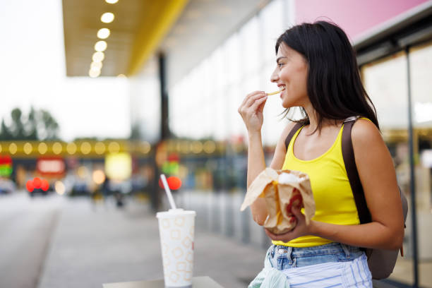 woman eating fast food in the city - junk food stock pictures, royalty-free photos & images
