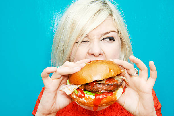 woman eating hamburger - junk food stock pictures, royalty-free photos & images