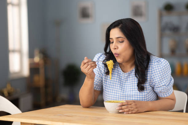 woman eating hot and spicy noodle at home stock photo - junk food stock pictures, royalty-free photos & images